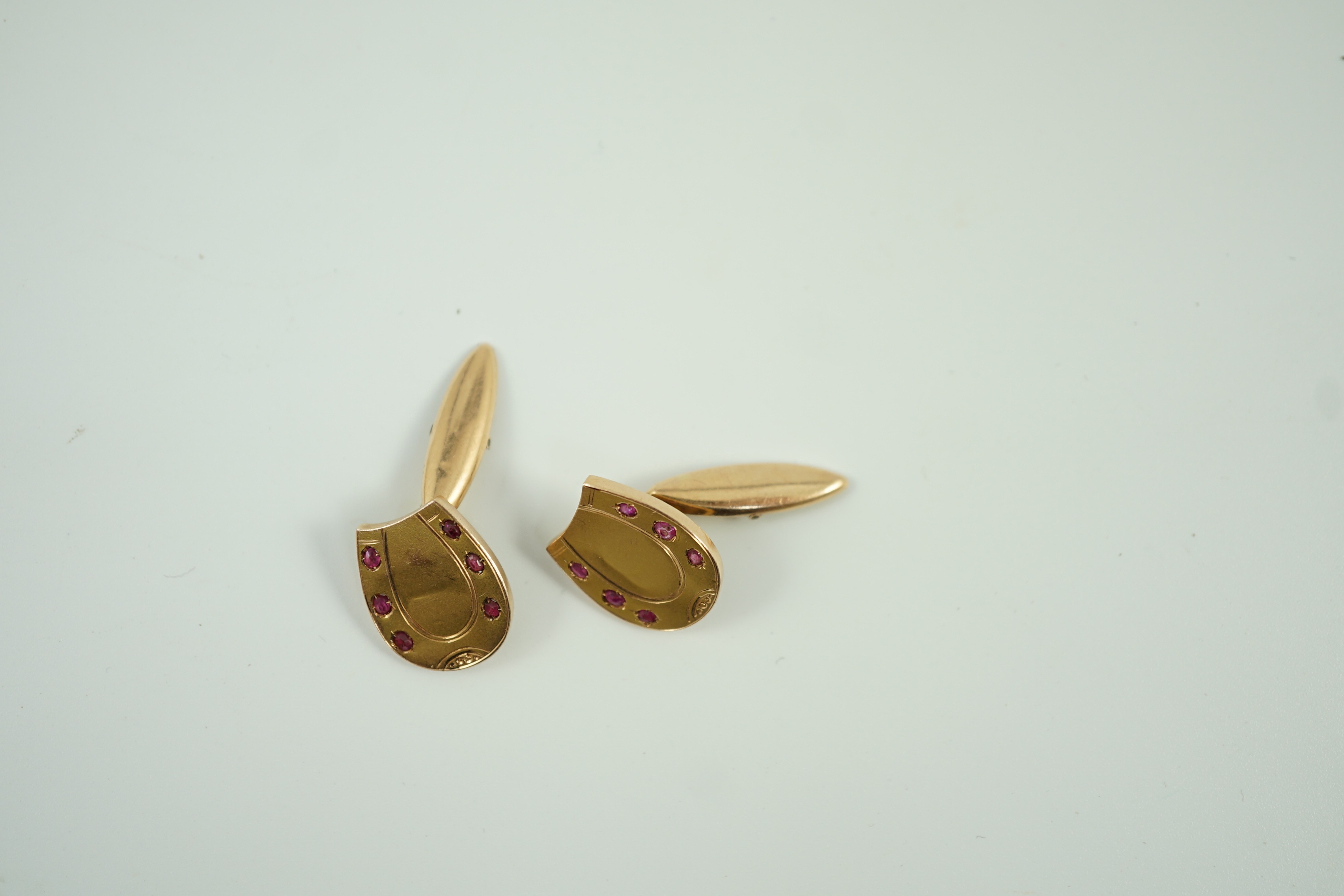 A pair of early 20th century Russian 56 zolotnik yellow metal and ruby set horseshoe shaped cufflinks, 16mm, gross weight 3.9 grams.